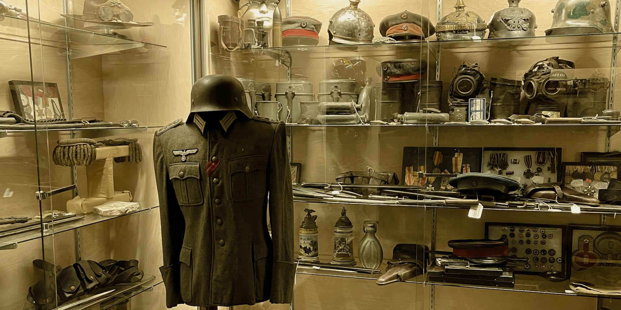 military vintage store uniform in front of glass case with multiple hats from all over the world