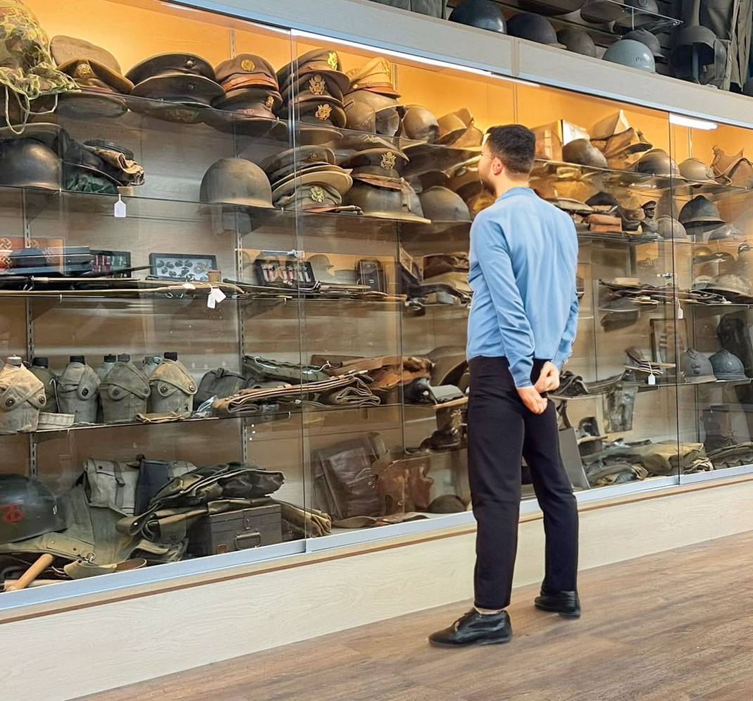 man standing in front of glass case at military vintage recon shop on garland road texas